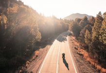 Hombre en moto en una carretera infinita rodeado de naturaleza