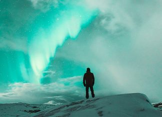 hombre solo mirando al cielo mientras disfruta de las auroras boreales