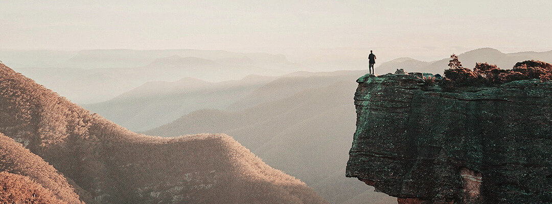 hombre en el borde de un acantilado con vistas al paisaje en su viaje